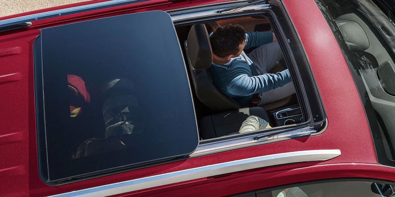 Red 2021 Chevrolet Equinox driving with sunroof open