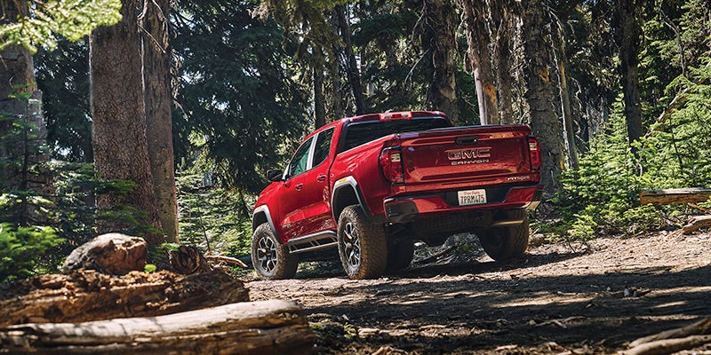 Red 2024 GMC Canyon driving through the woods