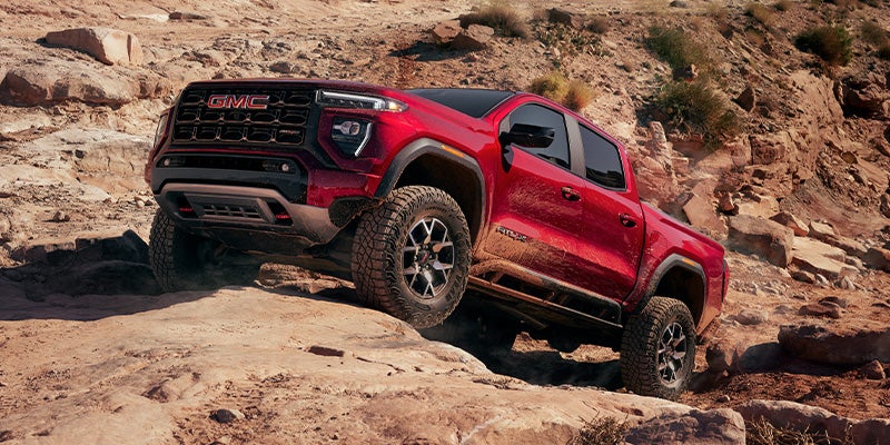 Red 2024 GMC Canyon driving up a cliff