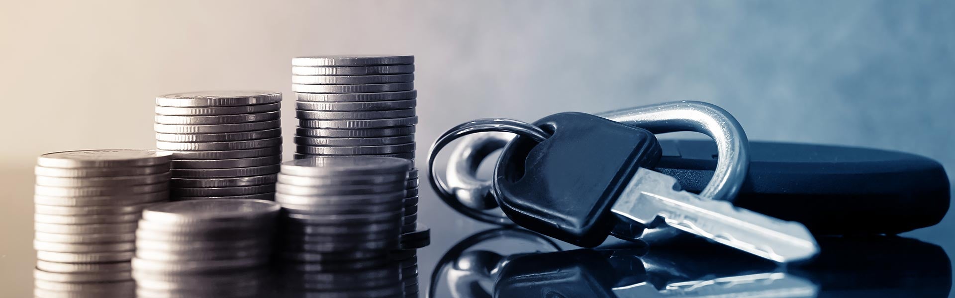 Stacks of coins and car keys resting on a desktop