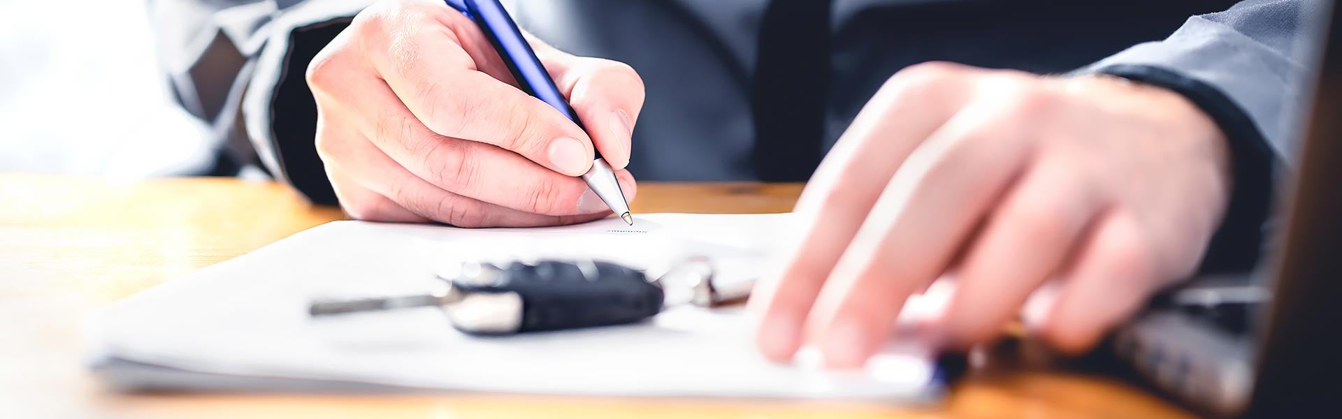 Customer signing financing paperwork with the vehicle keys at hand